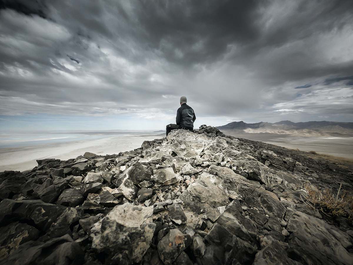 unnamed road man siting on gray rocky mountain wendover